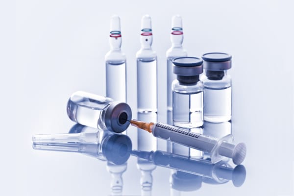 Syringe and multiple vials of clear medicine