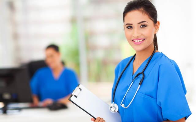 Young woman doctor in blue scrubs with clipboard and stethoscope
