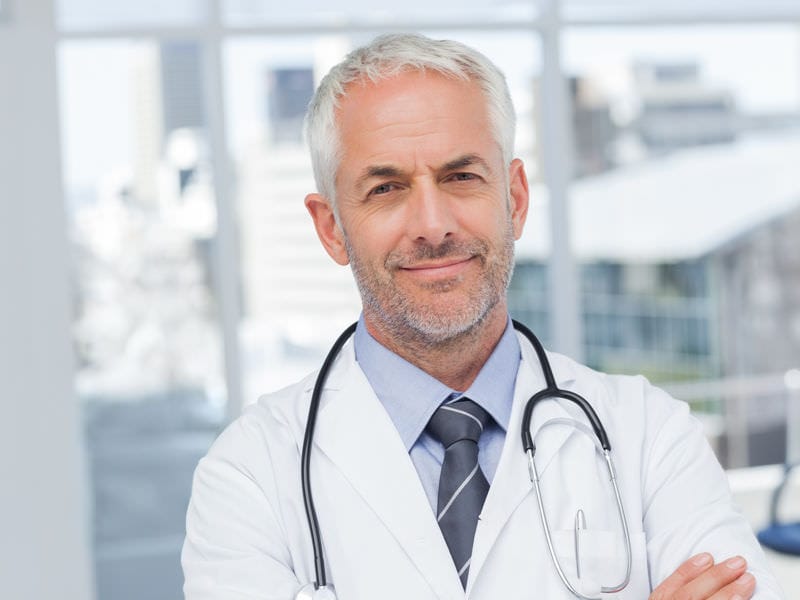 Mature silver-haired doctor with stethoscope diagnosing thoracic outlet syndrome