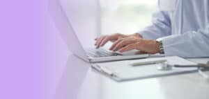 Doctor in white jacket typing blog on laptop