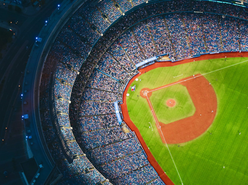 Major league baseball stadium at night with bright lights and large crowd of baseball fans.