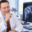 Illustrative portrait of Dr. Scott Werden reviewing thoracic outlet MRI images beside a shoulder anatomy model